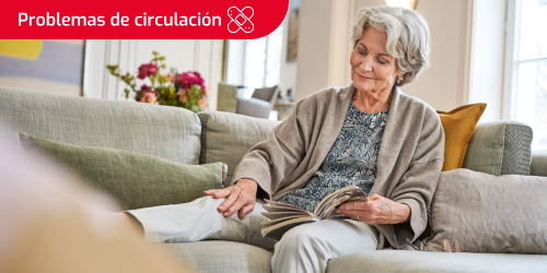 Etiqueta de problemas de circulación con icono de apósitos sobre la imagen de una mujer mayor sentada en el sofá que toca su rodilla derecha donde tiene una herida cicatrizando. Etiqueta de problemas de circulación con icono de apósitos sobre la imagen de una mujer mayor sentada en el sofá que toca su rodilla derecha donde tiene una herida cicatrizando.